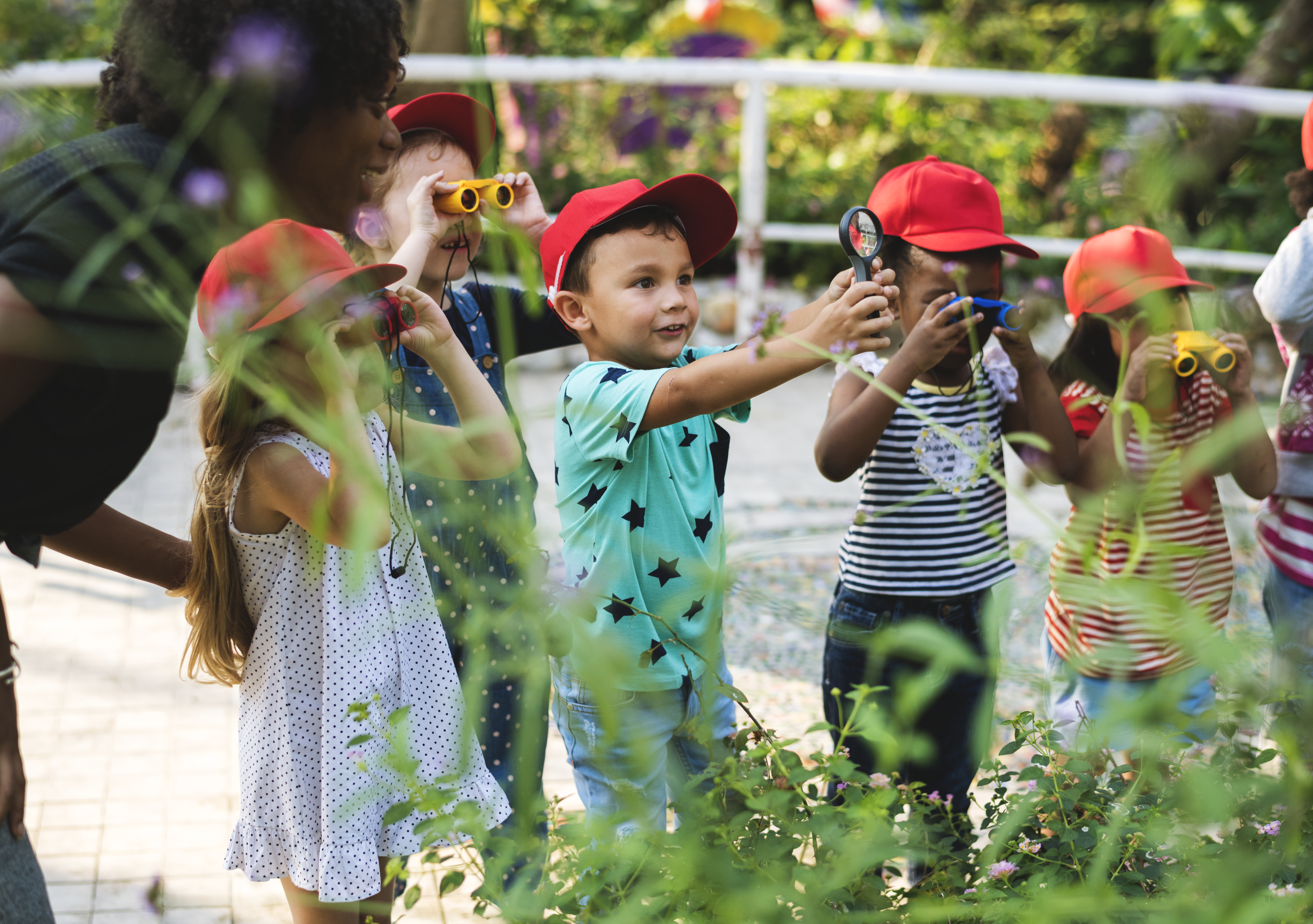 Zdjęcie przedstawiające grupę dzieci w parku, która przygląda się roślinom.