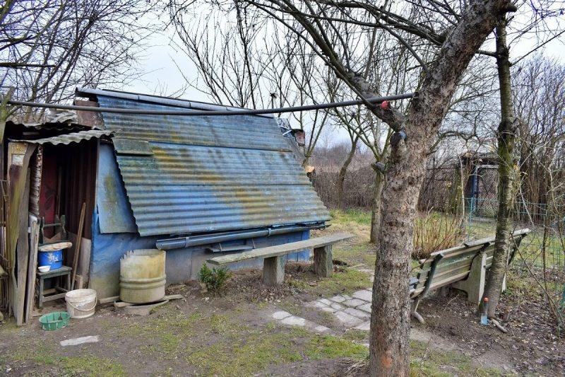 W lewym dolnym rogu altany widoczny wkopany w ziemię zbiornik na deszczówkę. działka